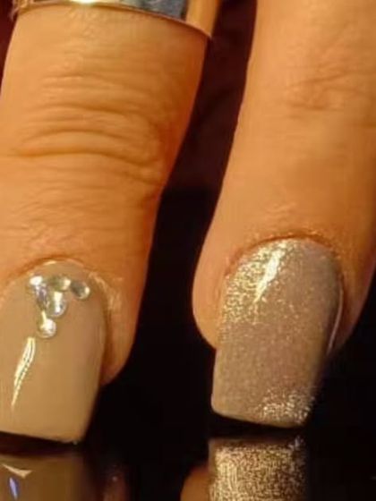 A chic and understated manicure with nude and glitter polishes, accented with single silver rhinestones.