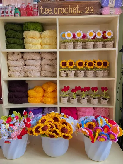 My yarn and flower shelf, with potted daisies, sunflowers, and hearts ready for orders.