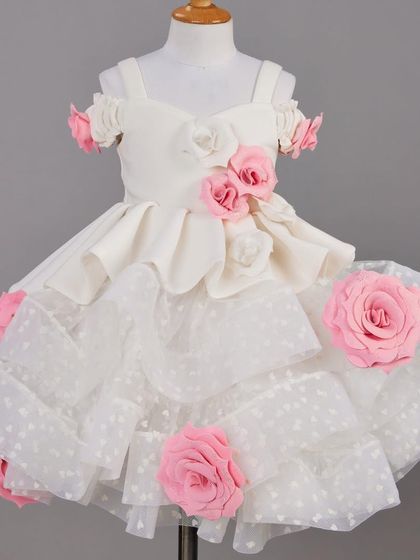 A beautiful white dress on a mannequin, adorned with pink and white roses and a polka dot overlay.