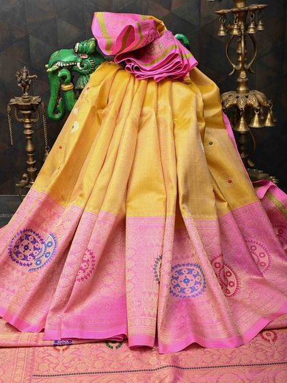 A bright yellow and pink silk saree with a unique circular motif design on the border. This cheerful and vibrant piece is perfect for festive celebrations.