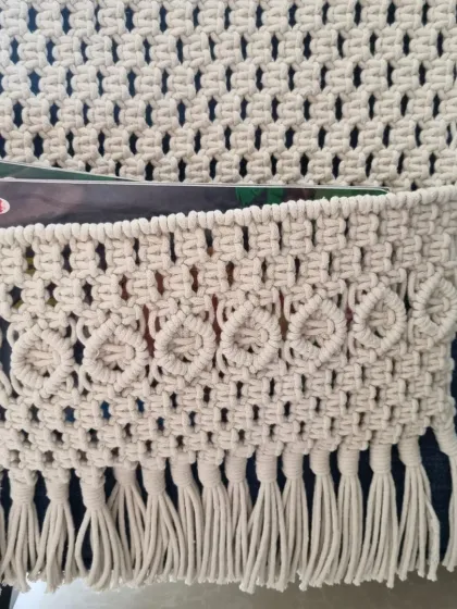 A detailed shot of the pocket on the wall organizer, showing the lovely heart-like knots and fringed bottom. It's perfect for keeping your essentials organized and within reach.