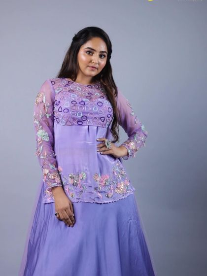 A full-length shot of our purple lehenga with its sheer, long-sleeved overlay. The combination of the solid skirt and the embroidered top creates a balanced and contemporary look.