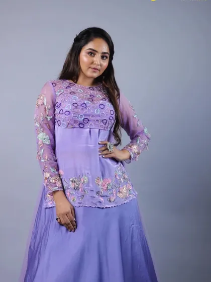 A full-length shot of our purple lehenga with its sheer, long-sleeved overlay. The combination of the solid skirt and the embroidered top creates a balanced and contemporary look.