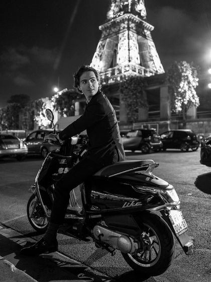 A candid moment in Paris at night, with the illuminated Eiffel Tower in the background. This black and white shot feels like a still from a classic film.