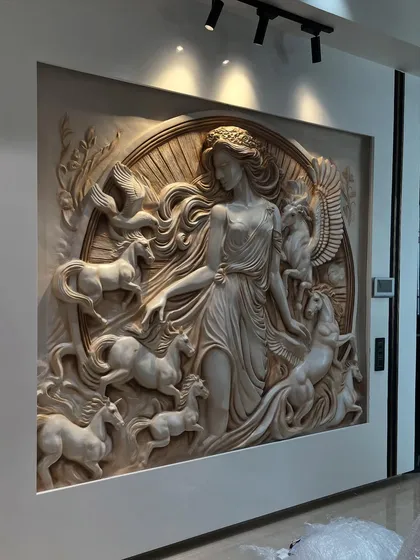Inspired by classical Greek art, this intricate fiber mural depicts a goddess with her horses, including a winged Pegasus. The entire piece is finished in a monochrome stone texture, with track lighting used to emphasize the deep relief and flowing details of the sculpture.