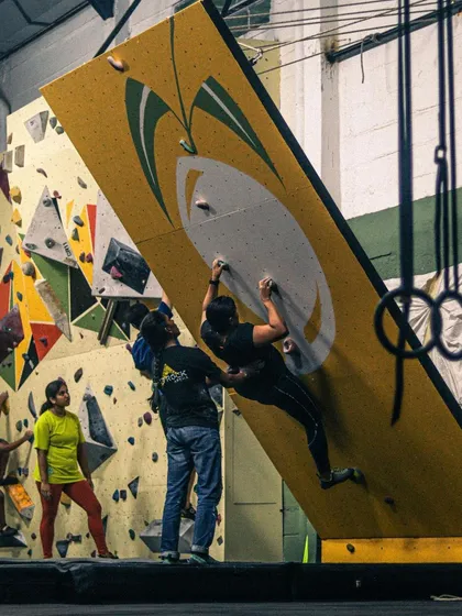 Safety and support are key, even for advanced climbers. Here, a spotter assists a climber on the MoonBoard, ensuring they can push their limits with confidence.