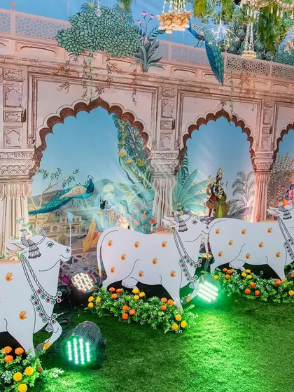 Detail shot of our Pichwai-themed decor, showcasing the hand-painted style wall panels depicting scenes from Vrindavan. The custom-made cow cutouts are placed along the walkway, adding a layer of authenticity and charm to the religious event.