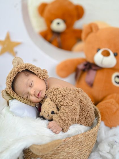 This little one is dreaming among the teddy bears. Using soft toys as props can add a playful and comforting element to newborn photos.