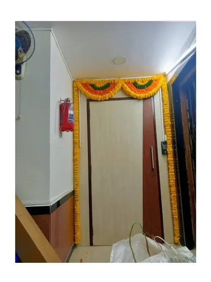 A simple and traditional door frame decoration using yellow marigold garlands and a toran at the top. This is a classic and budget-friendly way to add a festive touch to any home.