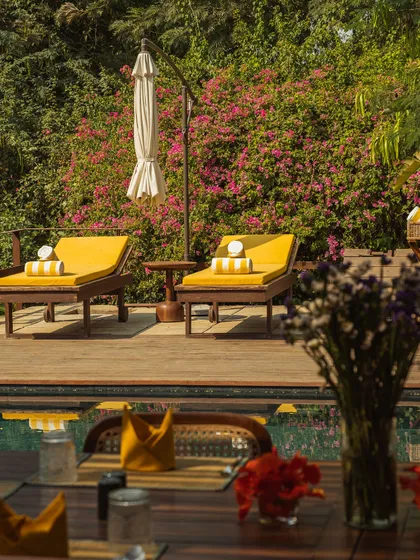 A view of the poolside loungers from a dining table on the deck, showing how the spaces for relaxation and dining flow together.