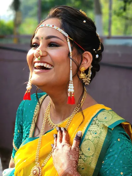 A candid shot capturing the infectious laughter of a happy bride. Her traditional Marathi look is completed with a mundavalya and glowing makeup.