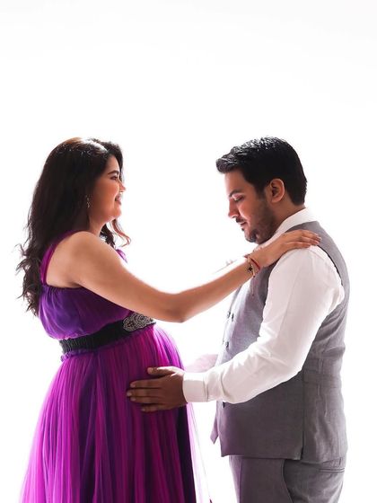 A classic studio maternity portrait. This happy couple is glowing, with the mom-to-be wearing a beautiful purple gown.