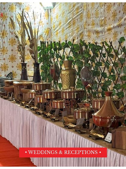 A traditional and grand buffet setup for a wedding reception. The arrangement features elegant copper and brass serving dishes on a beautifully decorated table, perfect for large celebrations.