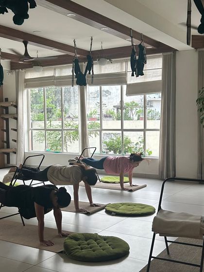 Students use chairs to support a plank pose, building core strength in a modified and accessible way.