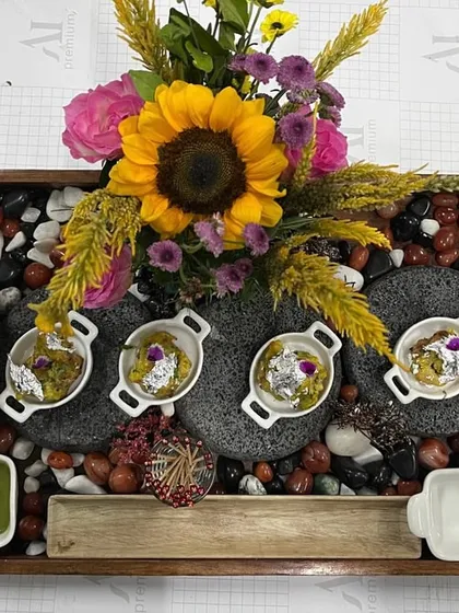 A stunning presentation of appetizers in individual white bowls, nestled among smooth stones and vibrant sunflowers. This display shows our commitment to creating food setups that are as beautiful as the event decor.