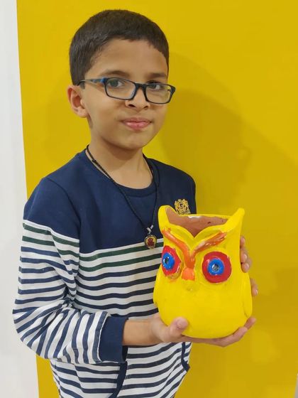 A proud boy holding his brightly painted owl planter. A perfect addition to any kid's room!
