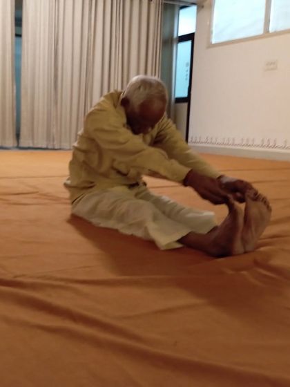 The same participant in Paschimottanasana, a seated forward bend, showing remarkable flexibility and dedication.