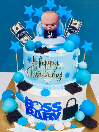 A fun two-tier Boss Baby theme cake. Decorated in shades of blue with stars, edible money, and the Boss Baby himself, this cake is perfect for a little one who rules the house.