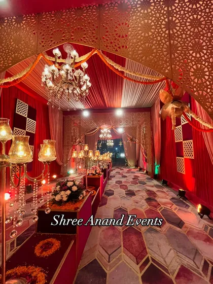A regal red and gold themed entrance corridor, lined with candelabras and featuring a geometric patterned floor.
