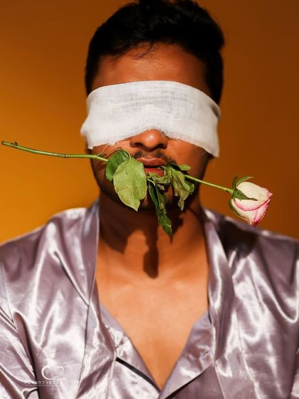 A stark and compelling version of the blindfolded concept. The lighting is sharp, emphasizing the texture of the satin robe and the blindfold.