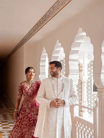 The groom waits with a gentle smile as his bride approaches through a sunlit palace corridor. This candid first look moment is filled with anticipation and the timeless beauty of royal architecture.