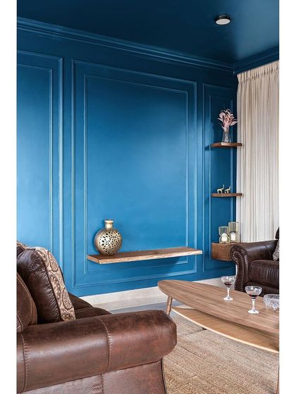 The other side of the entertainment room features the same bold teal on a wall with classic moulding. I added simple live-edge wood shelves to display decor, letting the wall color be the main statement.