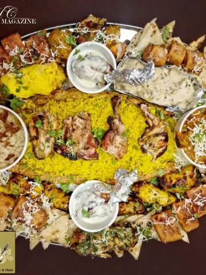 An abundant platter featuring Mandi rice surrounded by various chicken starters, creamy gravies, and naan. This thaal is a perfect example of a complete, shareable meal for a group.