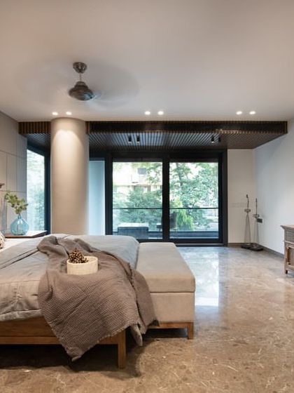 A wider view of the bedroom, showcasing the spacious layout, marble flooring, and a long wooden console that complements the bed frame.