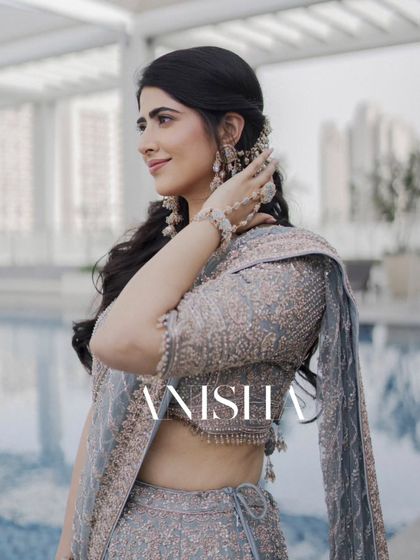 A stylish portrait of the bride, Anisha, in her elegant grey-blue engagement lehenga. Her confident pose and beautiful hairstyle are highlighted.