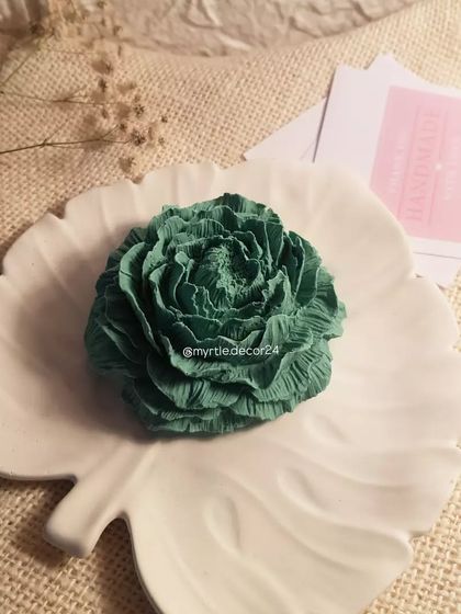 A deep green Peony aroma diffuser resting on a white monstera leaf tray. The color combination is inspired by nature and brings a sense of calm.