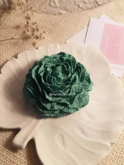 A deep green Peony aroma diffuser resting on a white monstera leaf tray. The color combination is inspired by nature and brings a sense of calm.