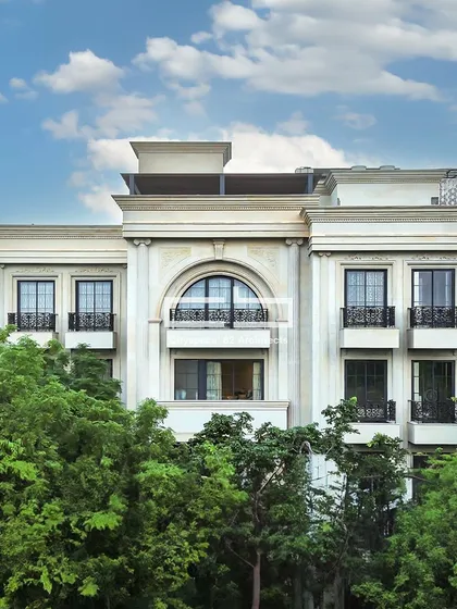 A daytime view of a facade that fuses modern design and classical aesthetics. An arched window adds dynamism to the edgy lines, while the white hues contribute to the classical feel.