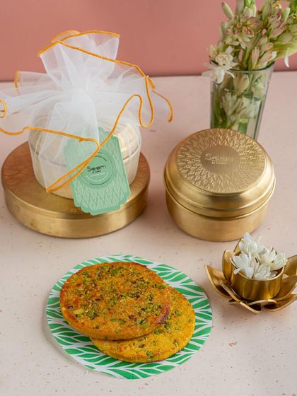 A beautifully packaged Badam Rotla in a brass tin, ready for gifting. This almond-based sweet is a unique festive favourite that is both delicious and thoughtfully made.