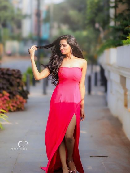 A full-length shot that captures the grace and flow of the pink gown. Her pose is confident and statuesque.