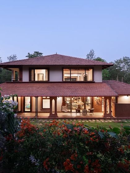 At dusk, the Dream Coffee Estate settles into the landscape, its warm interior lights creating a welcoming beacon in the forest. The design emphasizes a horizontal connection to the earth, with a sprawling ground floor that opens onto the surrounding gardens.