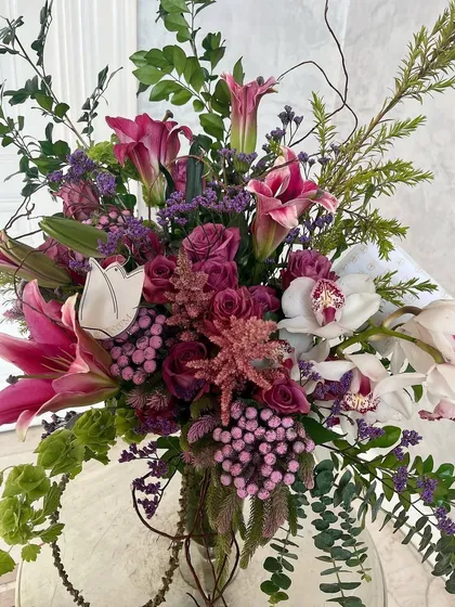 The snazziest arrangement with rare burgundy and pink flowers. Look for the shy white Cymbidium orchid amidst the Albiflora, Astilbe, and Oriental lilies.