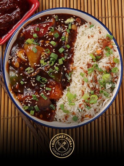A comforting bowl of Manchurian with fried rice, garnished with spring onions and sesame seeds. A classic Indo-Chinese dish executed to perfection.