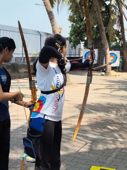 An instructor gives a quick tip to a young archer on the shooting line. Personalized guidance is part of our coaching philosophy.