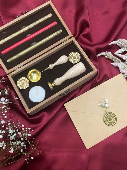 The contents of our wax seal stamp kit, including the custom stamp, melting spoon, candle, and various colored wax sticks.