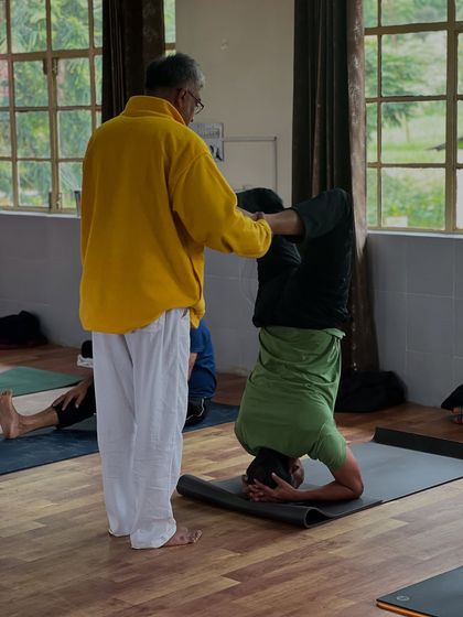 I provide a gentle adjustment to a student in a headstand variation, ensuring stability and proper form.
