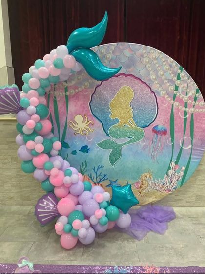 A full view of the mermaid-themed circular backdrop. The balloon garland uses shades of pink, purple, and teal to mimic the colors of the ocean.