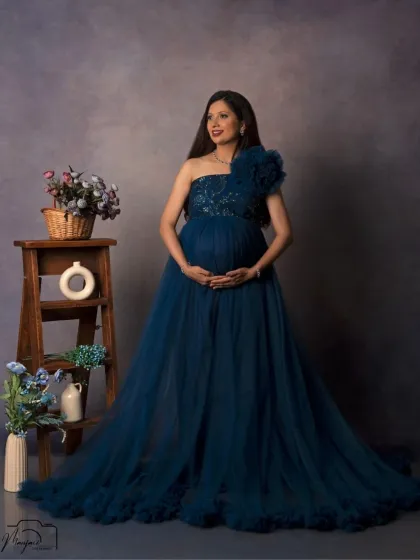 A stunning solo portrait of the mother-to-be in a gorgeous one-shoulder teal gown, looking serene and confident.