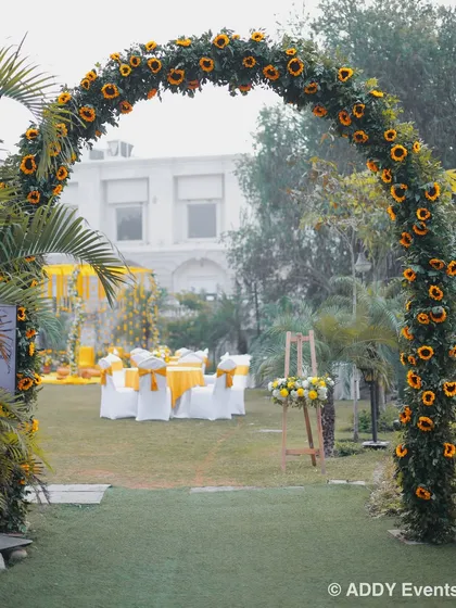 A beautiful sunflower arch creates a sunny and welcoming entrance to the Haldi celebration lawn.