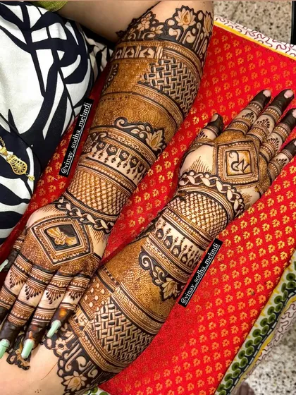 A traditional back-hand design with geometric patterns and personalized initials. The dark stain indicates the high quality of our henna paste.