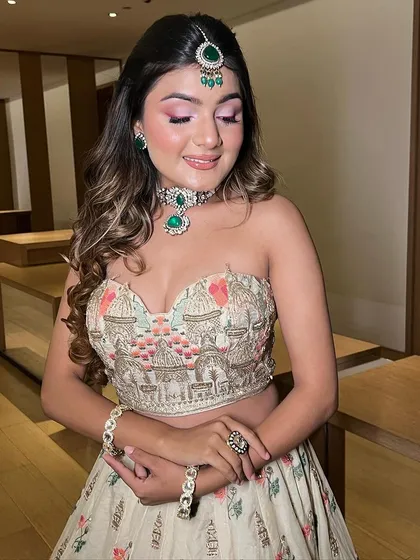A beautiful Haldi look with a pop of pink on the eyes. The makeup is fresh and dewy, complementing her floral lehenga and emerald jewelry.