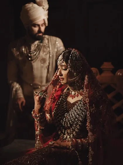 A quiet, intimate portrait of the couple. The bride's stunning red lehenga contrasts beautifully with the groom's ivory sherwani.