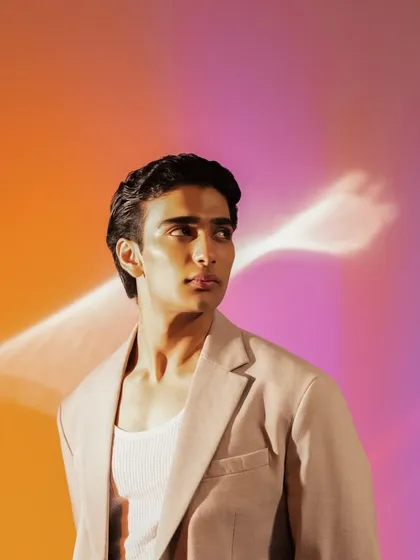 A profile shot with artistic lighting. The highlighter catches the light beautifully, defining his cheekbones.
