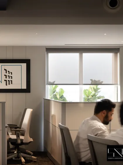 A quiet corner of the office, where clean lines and neutral tones create a focused work environment. The framed abstract art and natural light from the window contribute to a calm and uncluttered atmosphere.