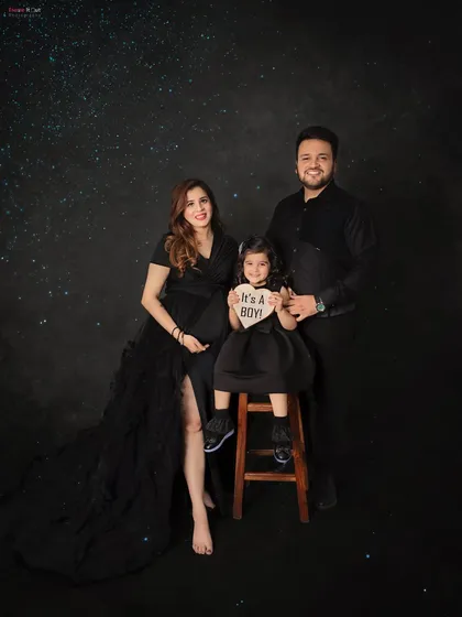 The whole family joins in to celebrate! This beautiful portrait captures the joy of a growing family, complete with a sweet "It's a Boy!" gender reveal sign against a magical starry backdrop.
