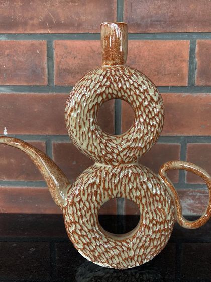 This unique, wheel-thrown double donut vase is also a functional teapot or watering can. It's a playful, artistic piece that is sure to be a conversation starter.